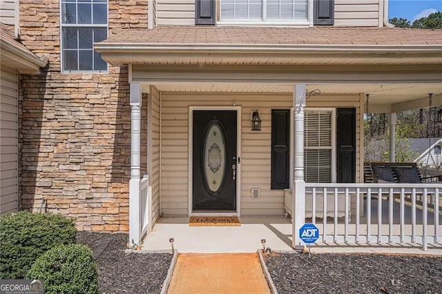 190 The Falls Blvd, Covington, GA 30016 - doorway to property featuring stone siding, a porch, and roof with shingles