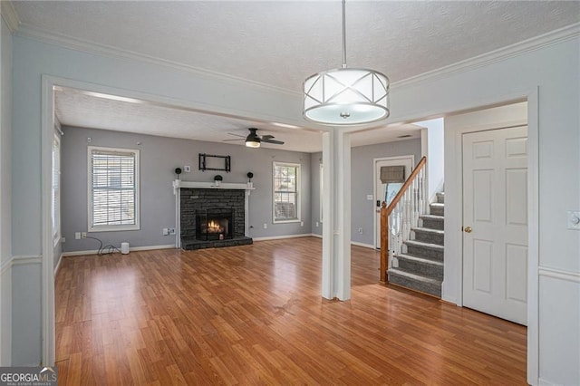 190 The Falls Blvd, Covington, GA 30016 - unfurnished living room with light wood finished floors, a ceiling fan, healthy amount of natural light, a fireplace, and crown molding