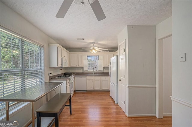 190 The Falls Blvd, Covington, GA 30016 - kitchen featuring white appliances, a ceiling fan, light wood finished floors, a sink, and dark countertops