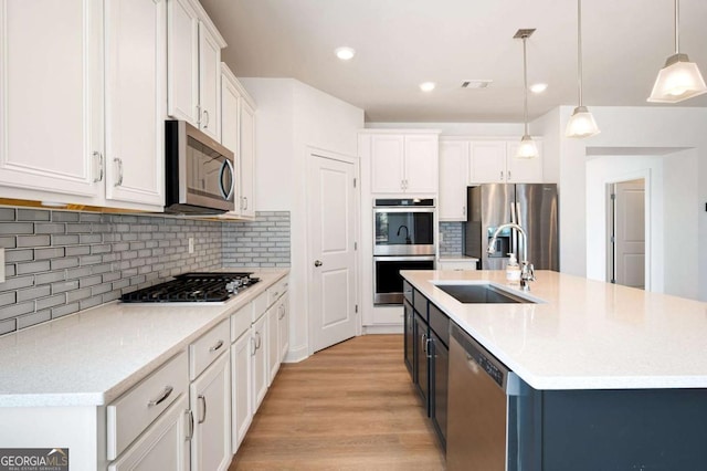 kitchen with appliances with stainless steel finishes, white cabinets, a sink, and visible vents