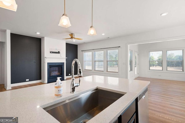 kitchen featuring open floor plan, a glass covered fireplace, a sink, and a healthy amount of sunlight