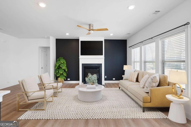 living room with recessed lighting, visible vents, a ceiling fan, a glass covered fireplace, and wood finished floors