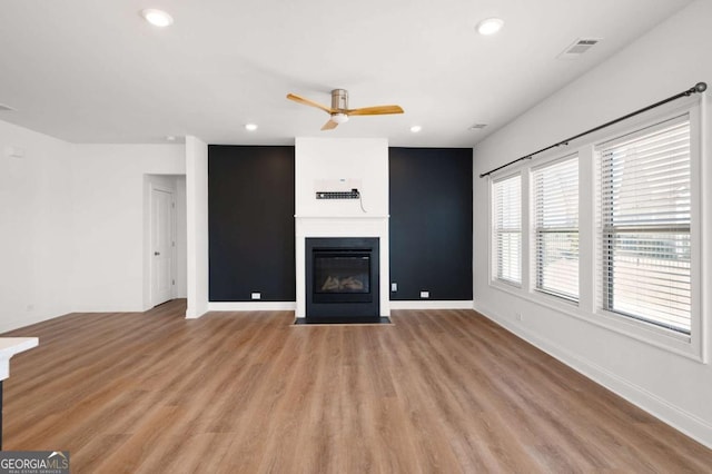 unfurnished living room featuring a fireplace with flush hearth, recessed lighting, light wood-style flooring, and baseboards