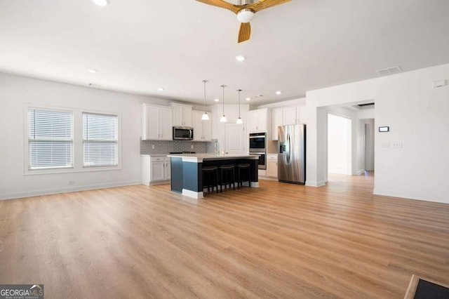 kitchen featuring white cabinets, light wood-style floors, stainless steel appliances, and open floor plan