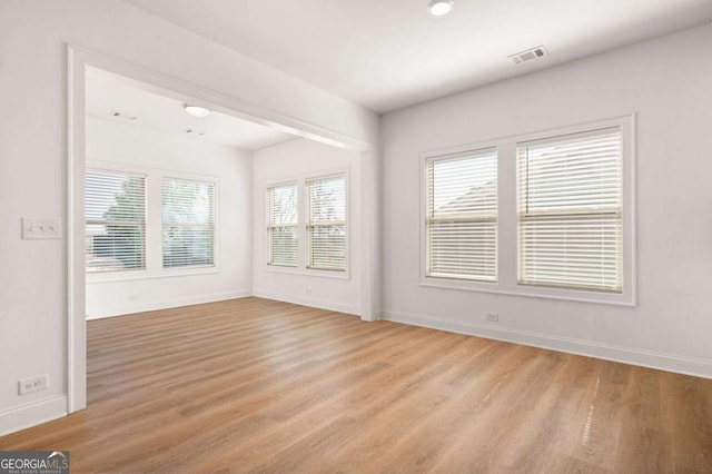 empty room featuring light wood-style flooring, visible vents, and baseboards