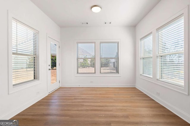 spare room with light wood-style floors, visible vents, and baseboards