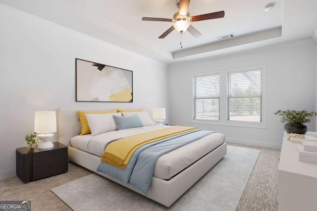 carpeted bedroom with a ceiling fan, a raised ceiling, visible vents, and baseboards