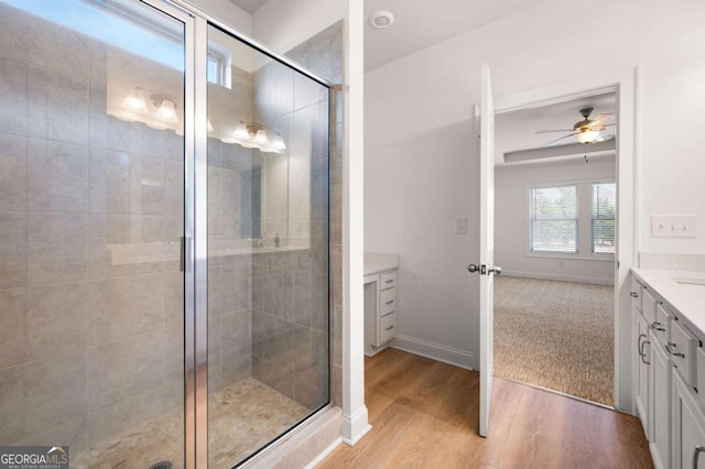 full bath featuring wood finished floors, a shower stall, vanity, and baseboards