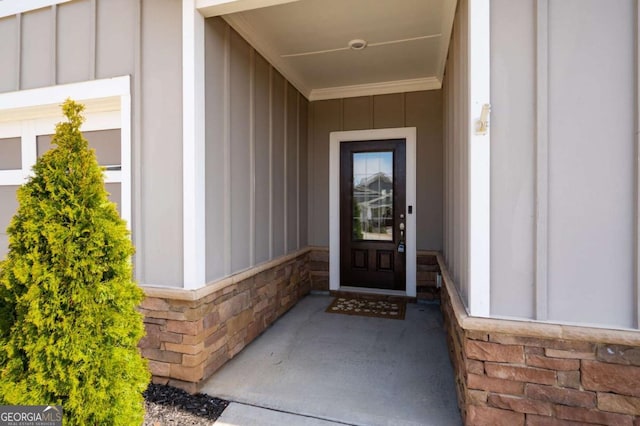 property entrance with board and batten siding and stone siding