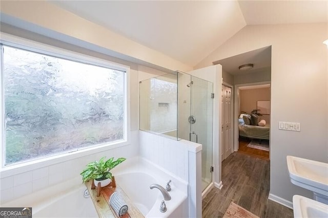 bathroom featuring a stall shower, ensuite bathroom, wood finished floors, a bath, and vaulted ceiling