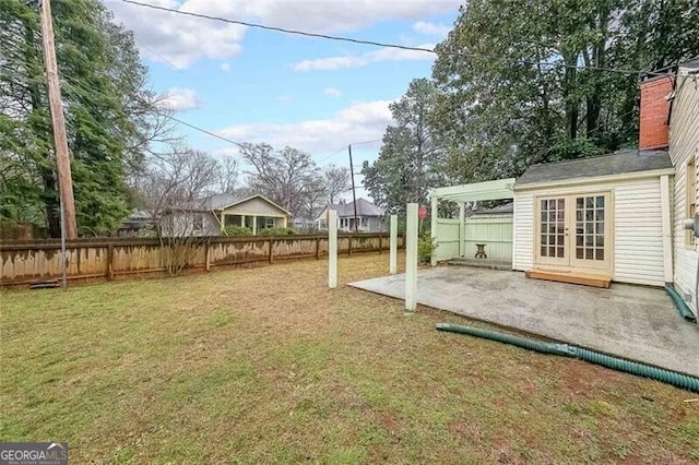 view of yard with french doors, fence, and a patio area