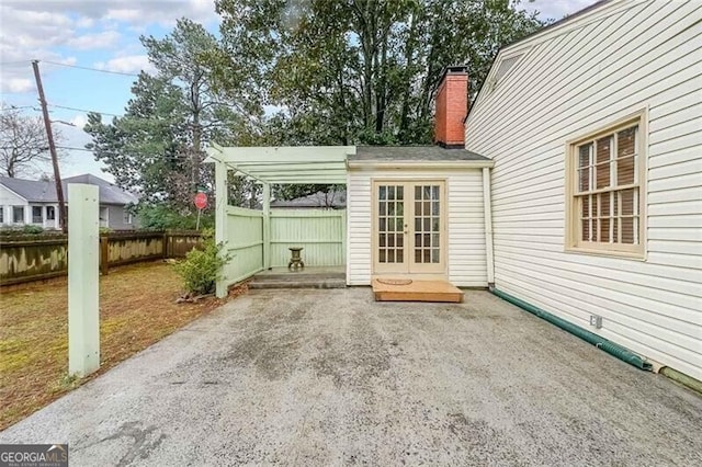 view of patio with a carport, french doors, and fence