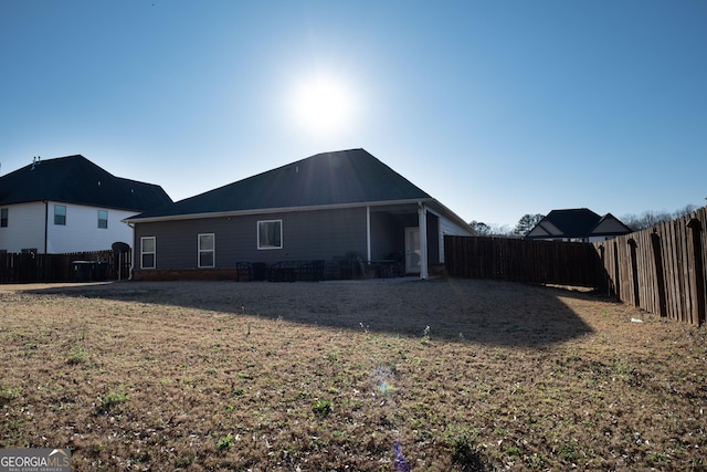 back of property with a fenced backyard and a lawn