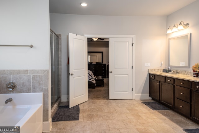 bathroom with a bath, a shower stall, vanity, and baseboards