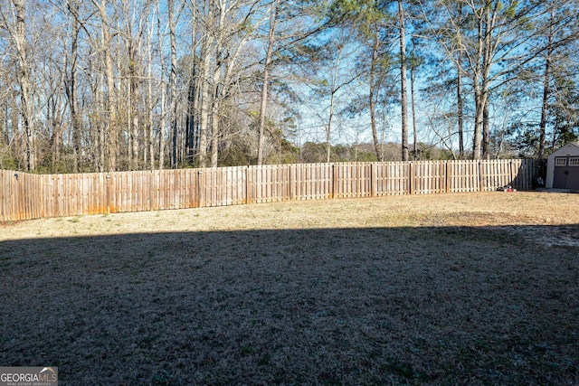 view of yard with an outbuilding, a fenced backyard, and a storage unit