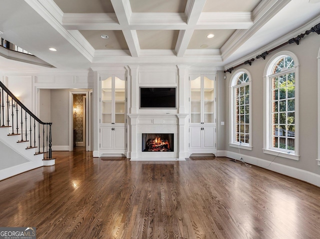 unfurnished living room with a large fireplace, coffered ceiling, ornamental molding, beamed ceiling, and wood finished floors