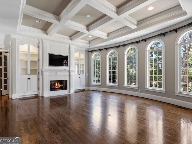 unfurnished living room with dark wood finished floors, beamed ceiling, a glass covered fireplace, and a wealth of natural light