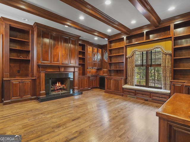 unfurnished living room with light wood finished floors, ornamental molding, beamed ceiling, and a high end fireplace