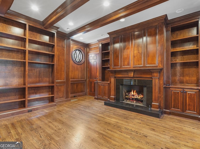 unfurnished living room with beamed ceiling, wood finished floors, a high end fireplace, and crown molding