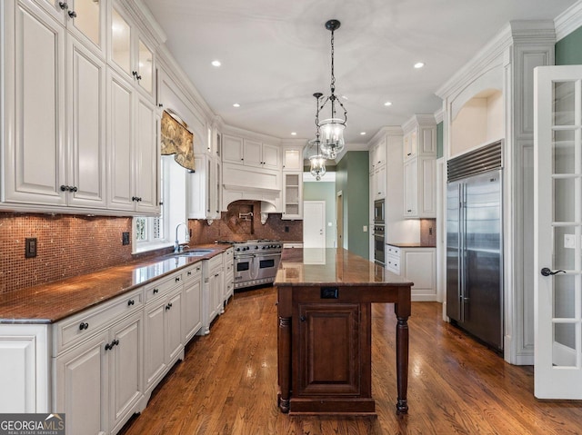 kitchen with white cabinetry, premium range hood, and built in appliances