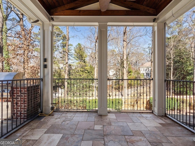 unfurnished sunroom featuring lofted ceiling with beams