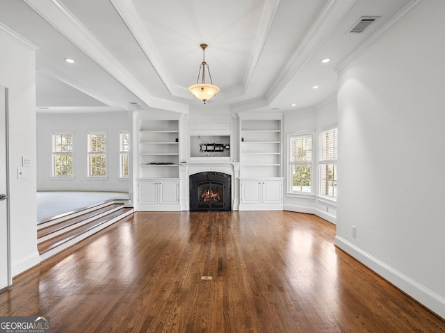 unfurnished living room featuring a warm lit fireplace, baseboards, a tray ceiling, and wood finished floors