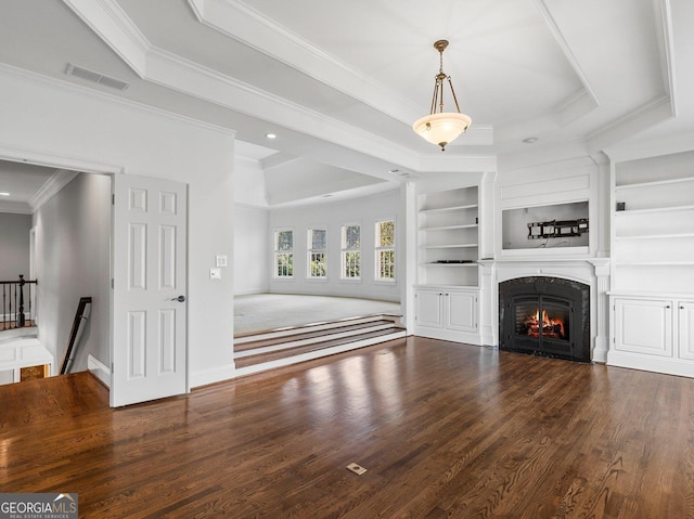 unfurnished living room with a warm lit fireplace, built in features, visible vents, a raised ceiling, and wood finished floors