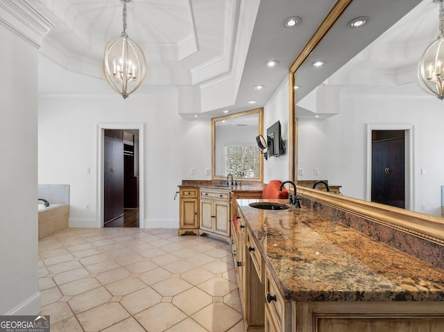 kitchen with ornamental molding, a tray ceiling, a sink, and an inviting chandelier