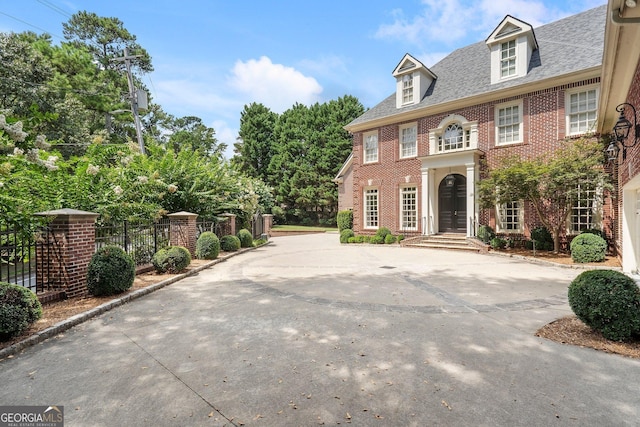 georgian-style home featuring fence and brick siding