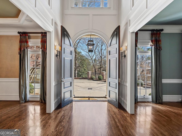 entryway featuring ornamental molding, dark wood-style flooring, and a high ceiling