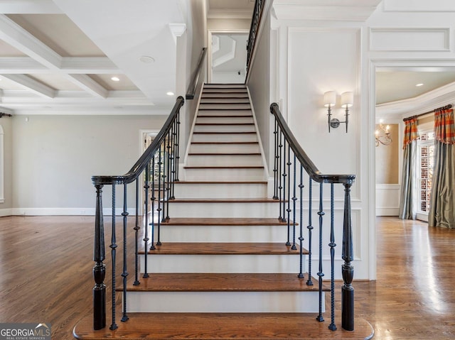 staircase featuring ornamental molding, beamed ceiling, coffered ceiling, and wood finished floors