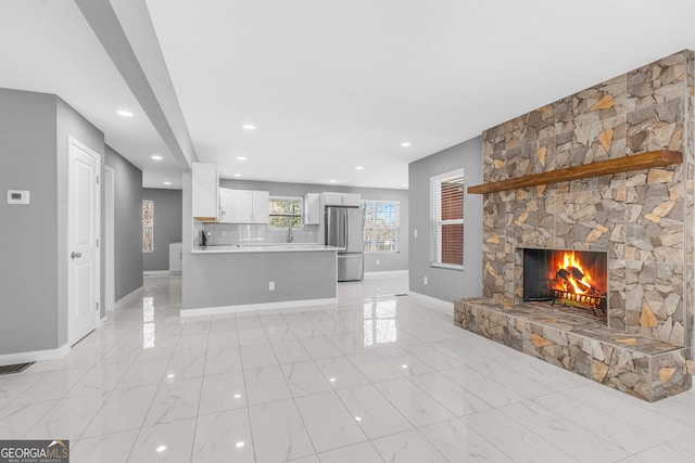 unfurnished living room featuring a fireplace, a sink, visible vents, baseboards, and marble finish floor