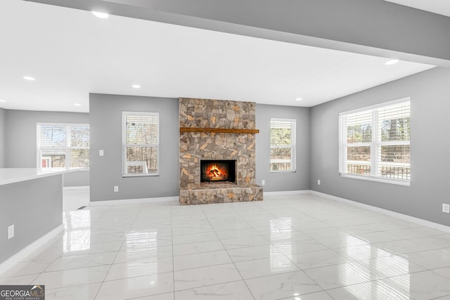 unfurnished living room with a stone fireplace, recessed lighting, and baseboards