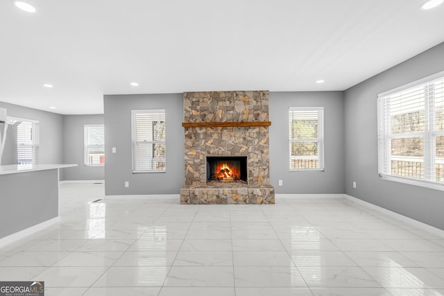 unfurnished living room featuring recessed lighting, baseboards, and a stone fireplace