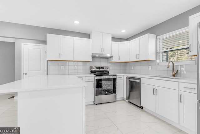 kitchen with marble finish floor, light countertops, appliances with stainless steel finishes, a sink, and under cabinet range hood