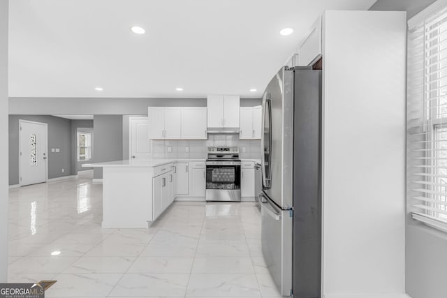 kitchen featuring white cabinets, decorative backsplash, a peninsula, marble finish floor, and stainless steel appliances