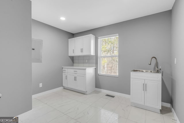 clothes washing area featuring marble finish floor, electric panel, visible vents, and a sink