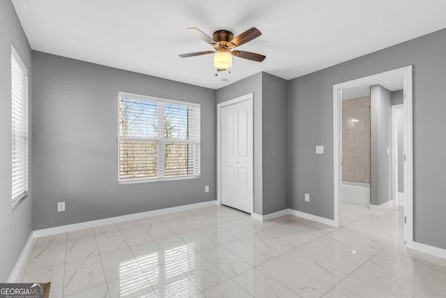 unfurnished bedroom with a closet, marble finish floor, and baseboards