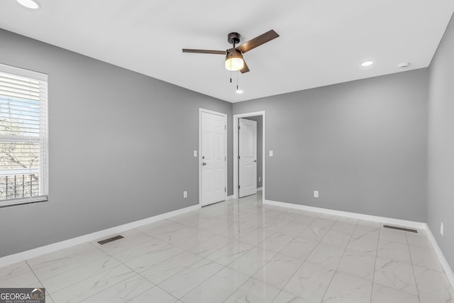 empty room with marble finish floor, visible vents, plenty of natural light, and baseboards