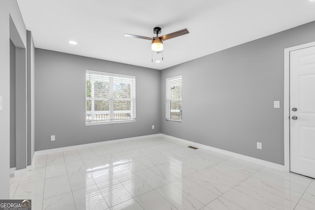 empty room featuring ceiling fan, marble finish floor, visible vents, and baseboards