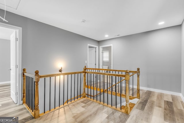 hallway featuring recessed lighting, wood finished floors, an upstairs landing, baseboards, and attic access