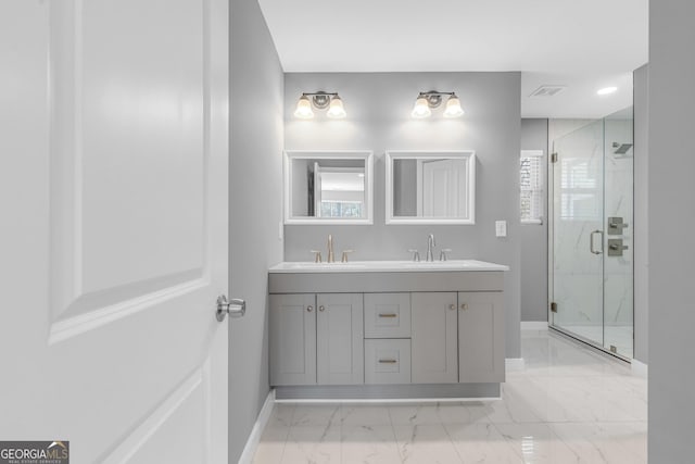 full bath with a sink, baseboards, marble finish floor, a marble finish shower, and double vanity