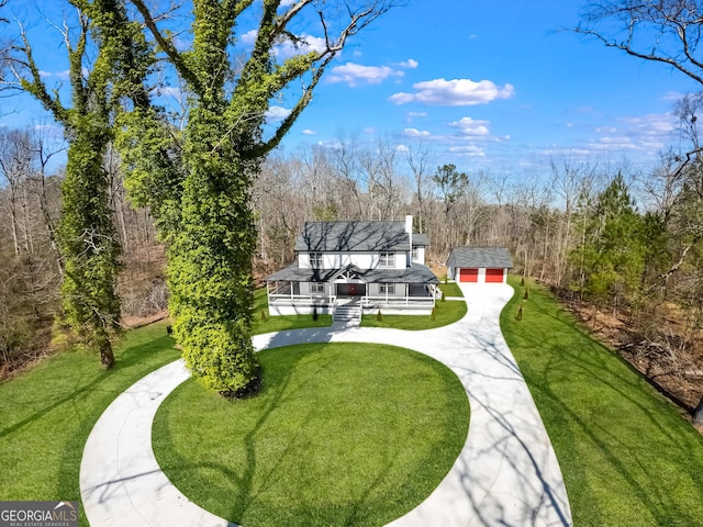 view of community with driveway, a yard, a deck, and an outdoor structure