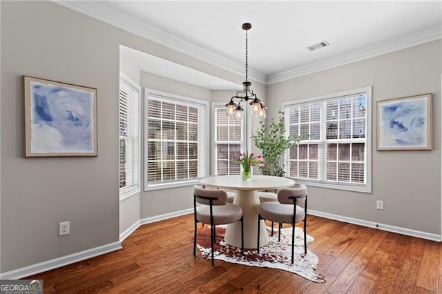 dining area with baseboards, visible vents, crown molding, and wood finished floors