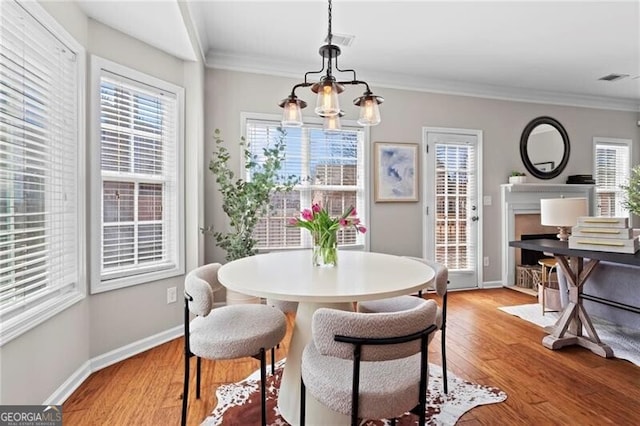 dining area featuring a chandelier, visible vents, baseboards, light wood-type flooring, and crown molding