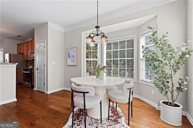 dining space featuring ornamental molding, wood finished floors, and baseboards