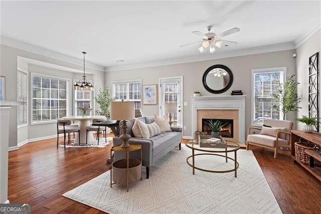 living room featuring ornamental molding, a fireplace, baseboards, and wood finished floors