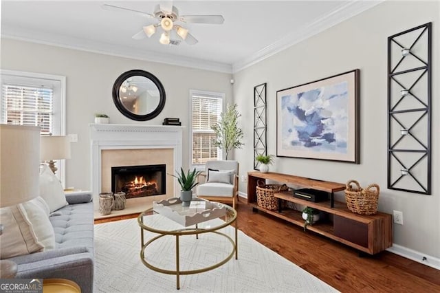 living area featuring baseboards, ornamental molding, wood finished floors, and a healthy amount of sunlight