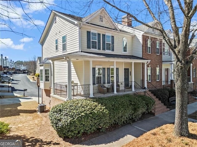 view of front of house featuring driveway, a chimney, metal roof, a standing seam roof, and a porch