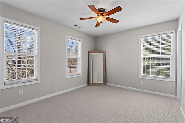 spare room featuring ceiling fan, visible vents, baseboards, and carpet flooring